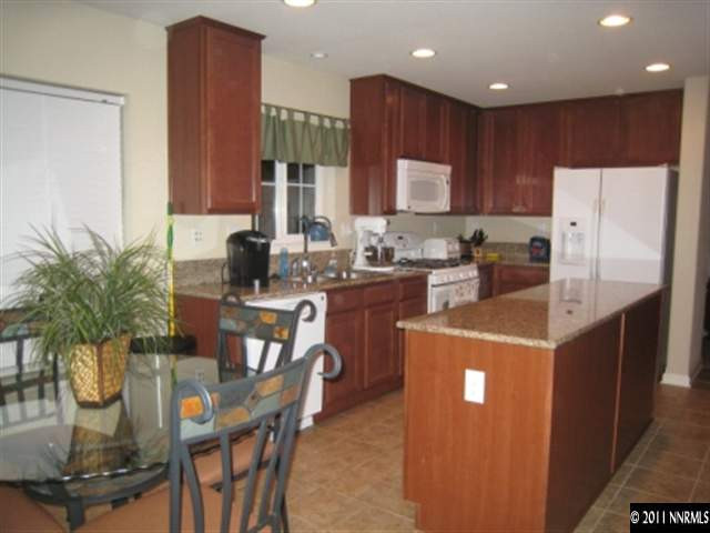 8960 Yeager Street Reno, NV 89506 - Photo 2 of 10 a kitchen with kitchen island granite countertop a sink a stove a refrigerator a dining table and chairs