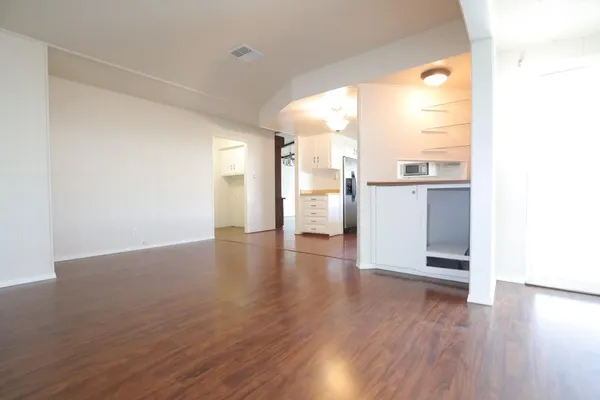 a view of a kitchen with a fridge and wooden floor