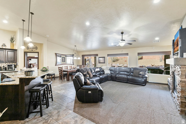 210 Talon Court Ivins, UT 84738 - Photo 11 of 60 Living area with a stone fireplace, a ceiling fan, lofted ceiling, recessed lighting, and light carpet