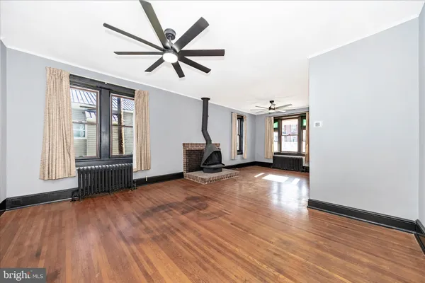 a view of empty room with wooden floor and fan