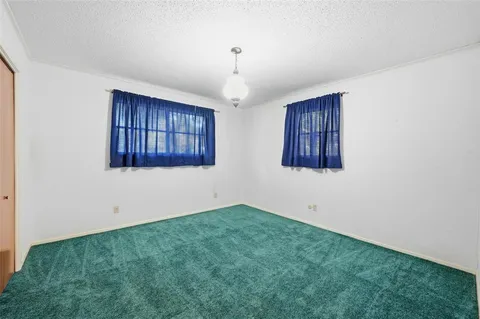 an empty room with windows and chandelier fan