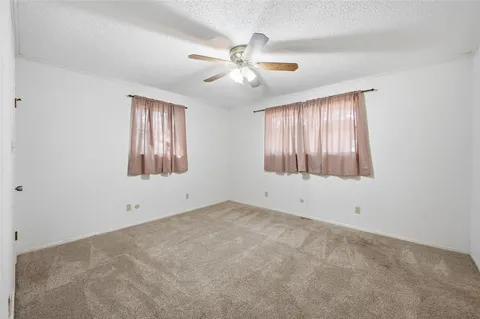 an empty room with window and ceiling fan