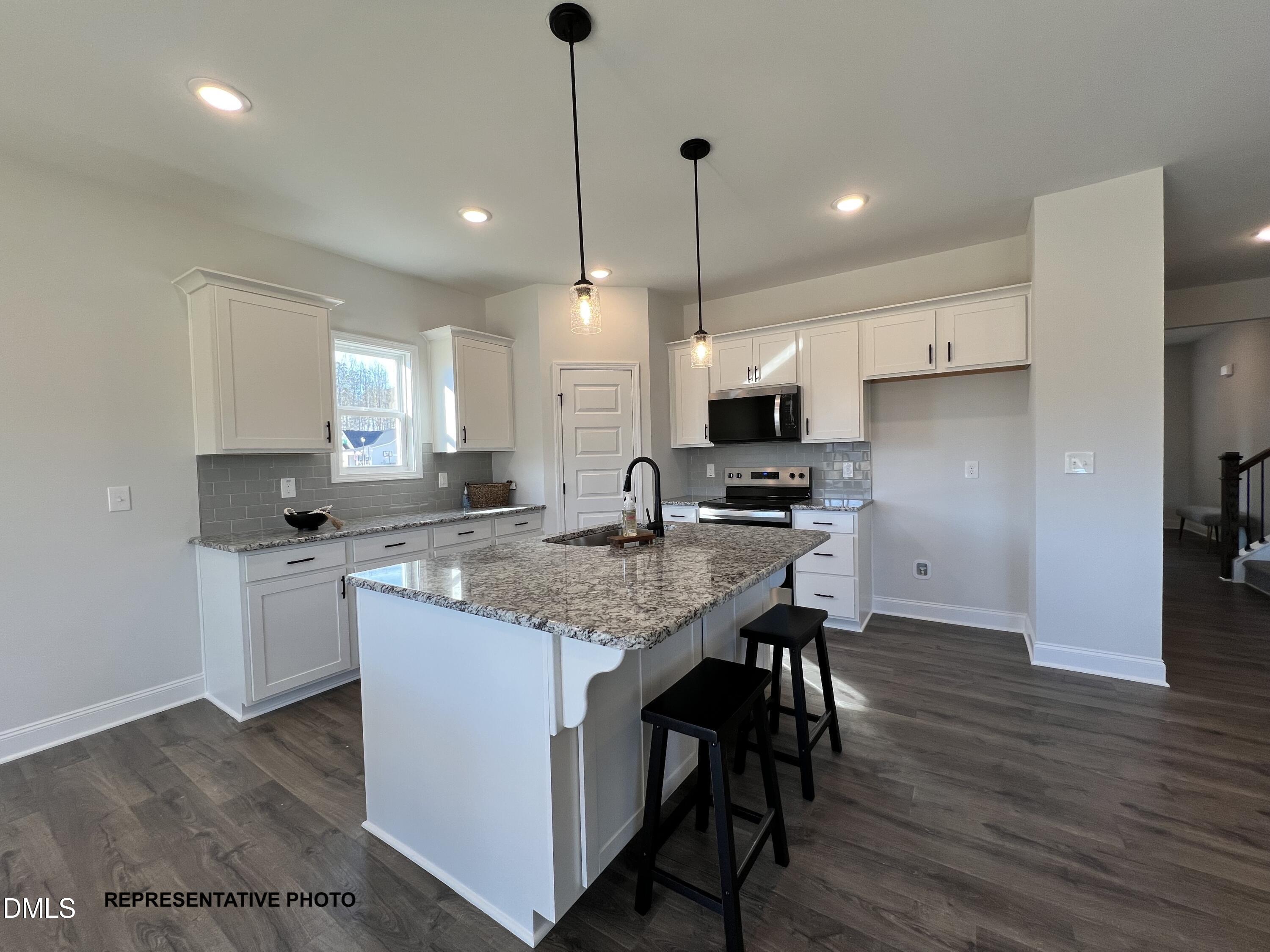 75 Cardovia Way Wendell, NC 27591 - Photo 2 of 17 a kitchen with kitchen island granite countertop a sink a counter space appliances and a cabinets