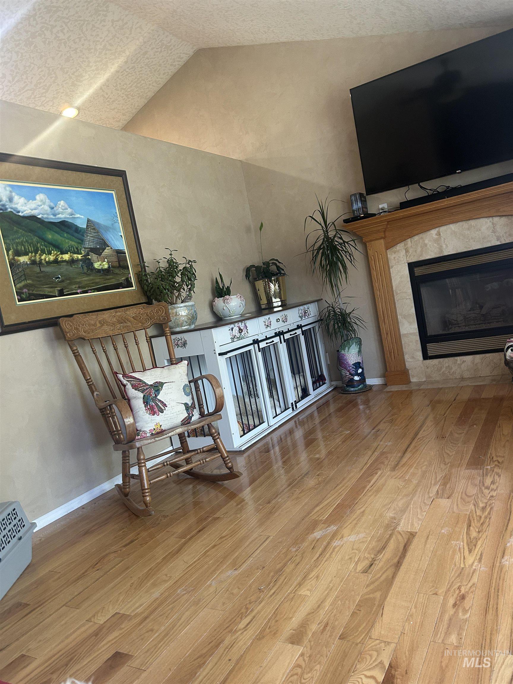 1444 East Doberman Street Meridian, ID 83642 - Photo 23 of 31 Living area featuring wood-finish flooring, a fireplace with a natural stone surround and wood mantel, and vaulted ceilings with recessed lighting