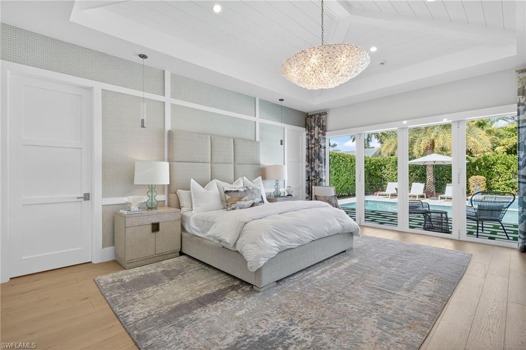 405 7th Avenue North Naples, FL 34102 - Photo 18 of 50 a spacious bedroom with a large bed and a chandelier