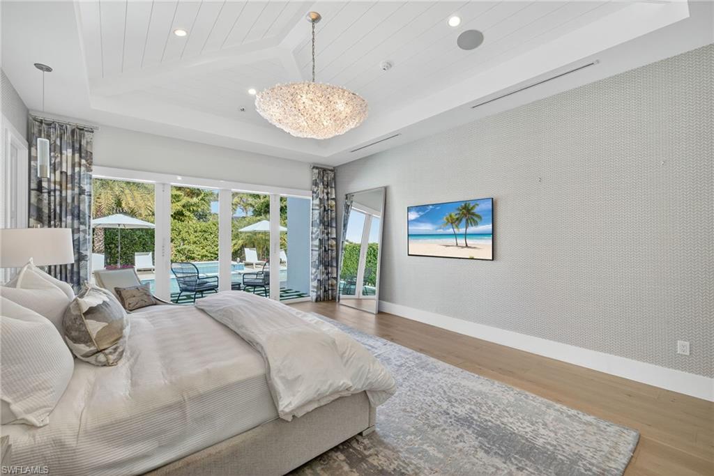 405 7th Avenue North Naples, FL 34102 - Photo 19 of 50 a spacious bedroom with a large bed and a chandelier
