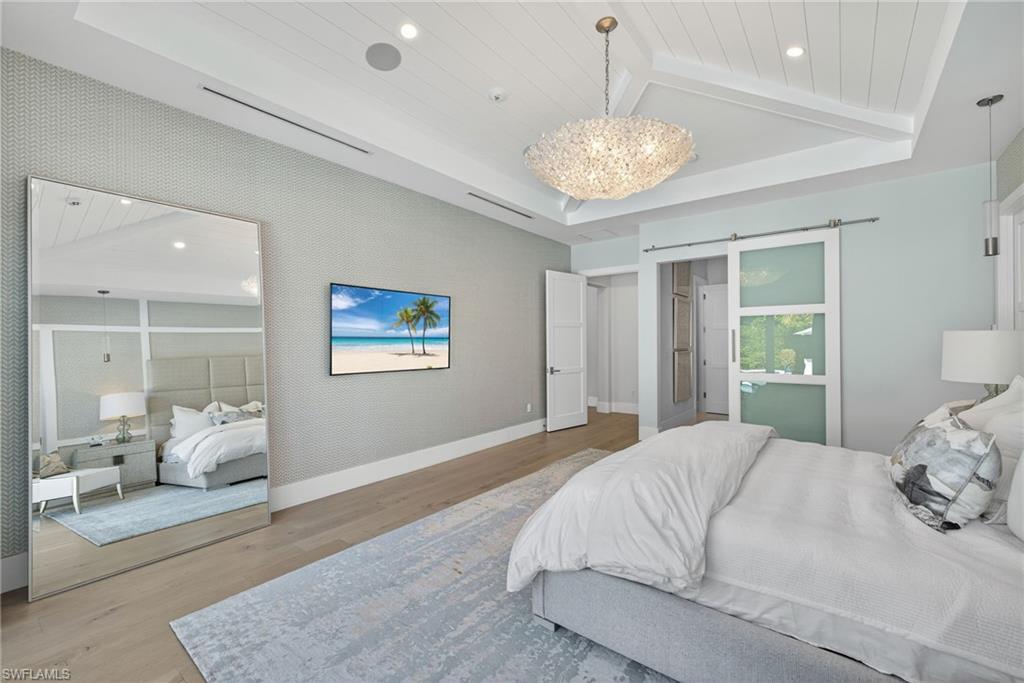 405 7th Avenue North Naples, FL 34102 - Photo 20 of 50 a bedroom with a large bed and a chandelier