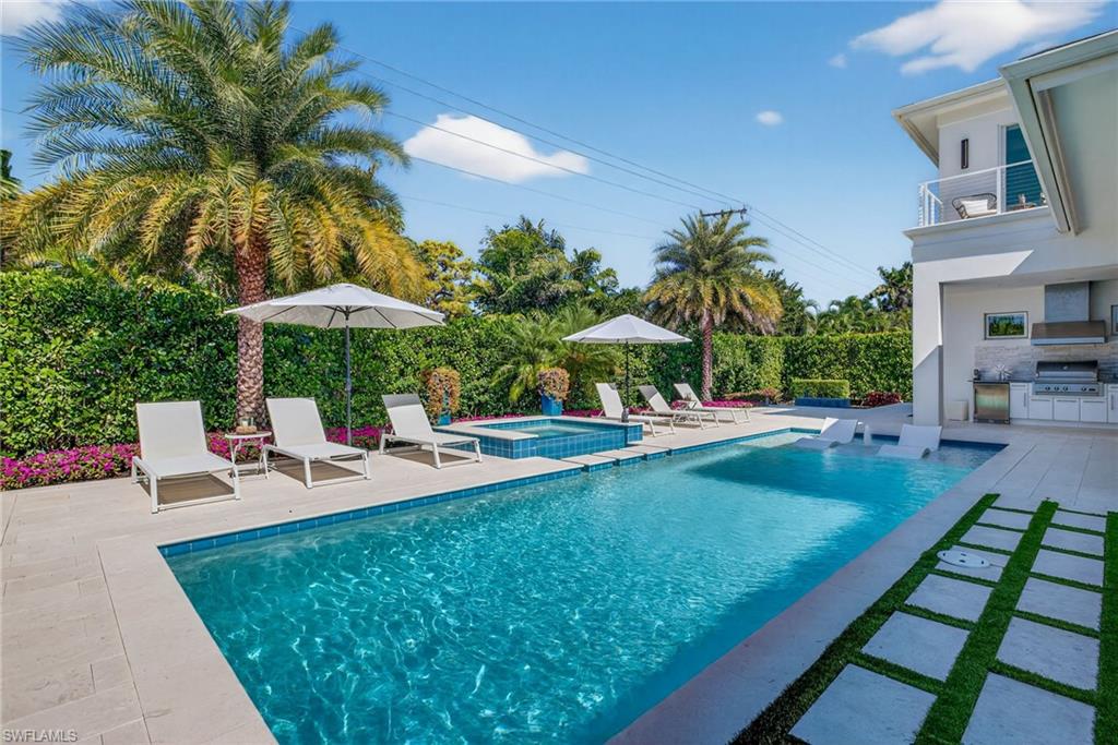 405 7th Avenue North Naples, FL 34102 - Photo 44 of 50 a view of a backyard with chairs and table under an umbrella with palm trees