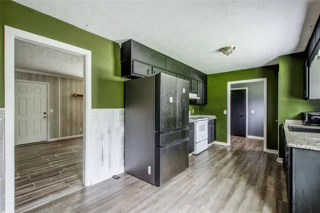 a kitchen with kitchen island wooden floor appliances and cabinets