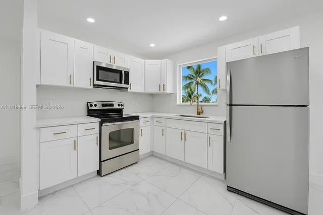 a kitchen with white cabinets stainless steel appliances and a refrigerator