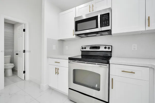 a kitchen with stainless steel appliances granite countertop white cabinets a stove a microwave and a refrigerator
