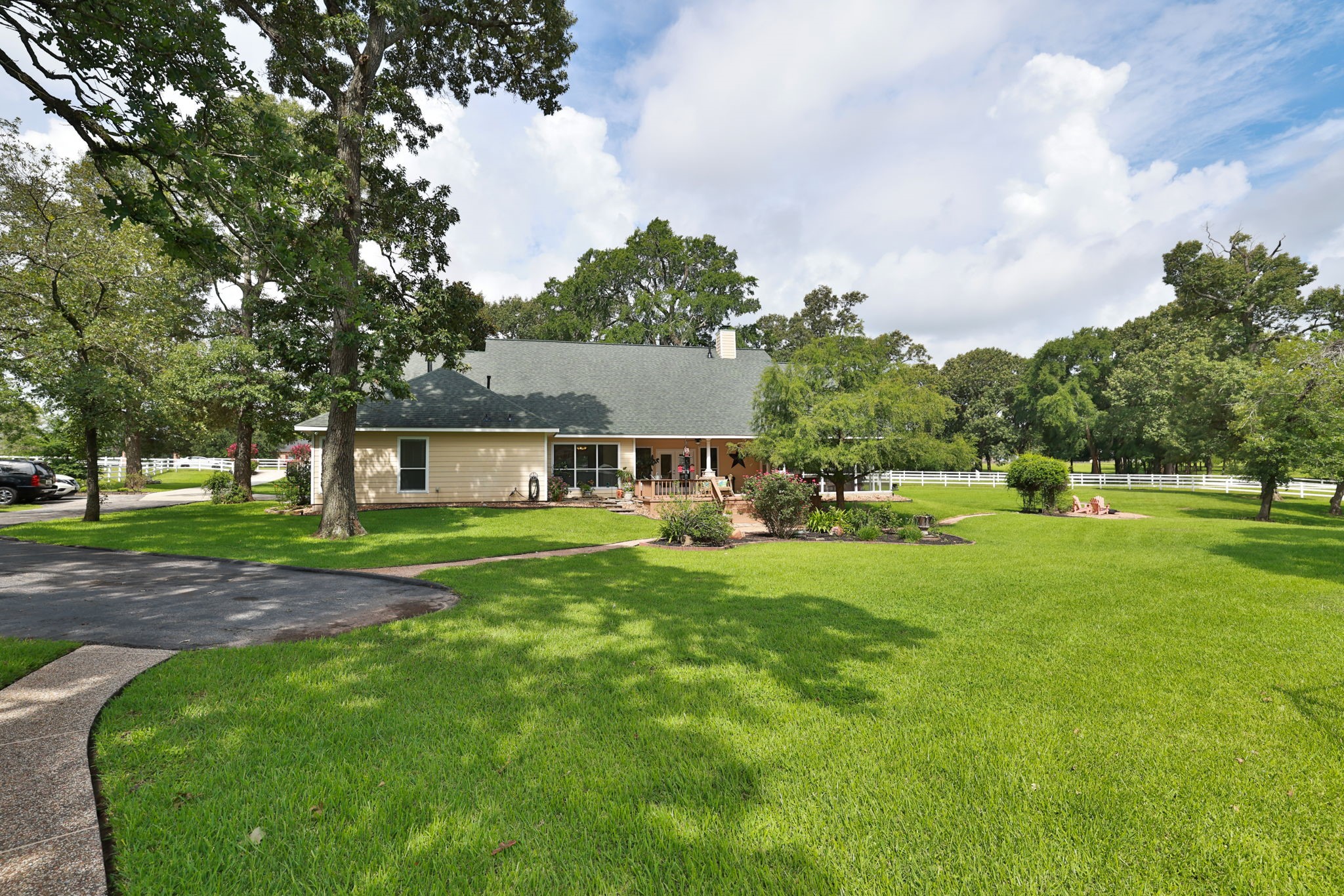 34310 High Point Drive Magnolia, TX 77355 - Photo 41 of 48 Charming home with a large, manicured lawn and mature trees. It features a spacious driveway, a welcoming porch, and is surrounded by lush greenery, perfect for privacy and outdoor activities.