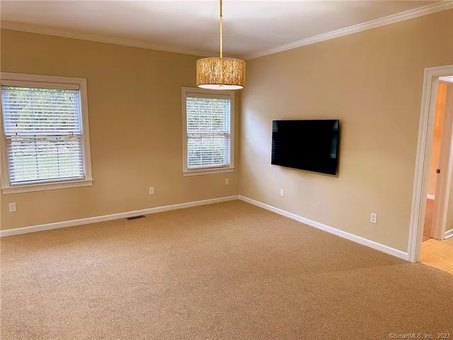 a view of an empty room with a window and a kitchen