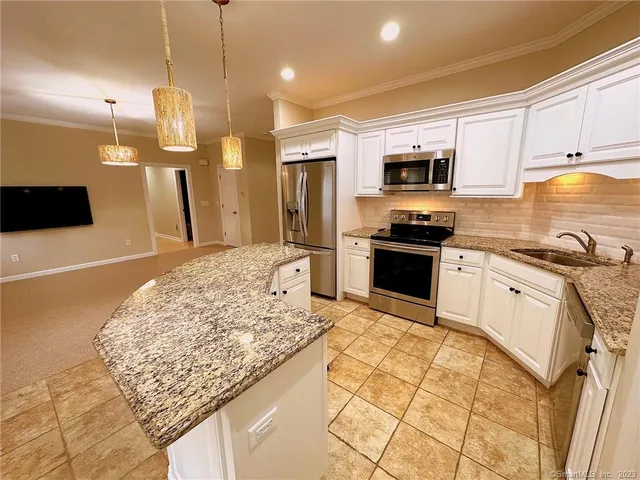 a kitchen with stainless steel appliances kitchen island granite countertop a sink stove and refrigerator