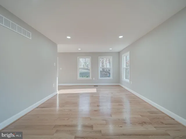 a view of empty room with wooden floor and window