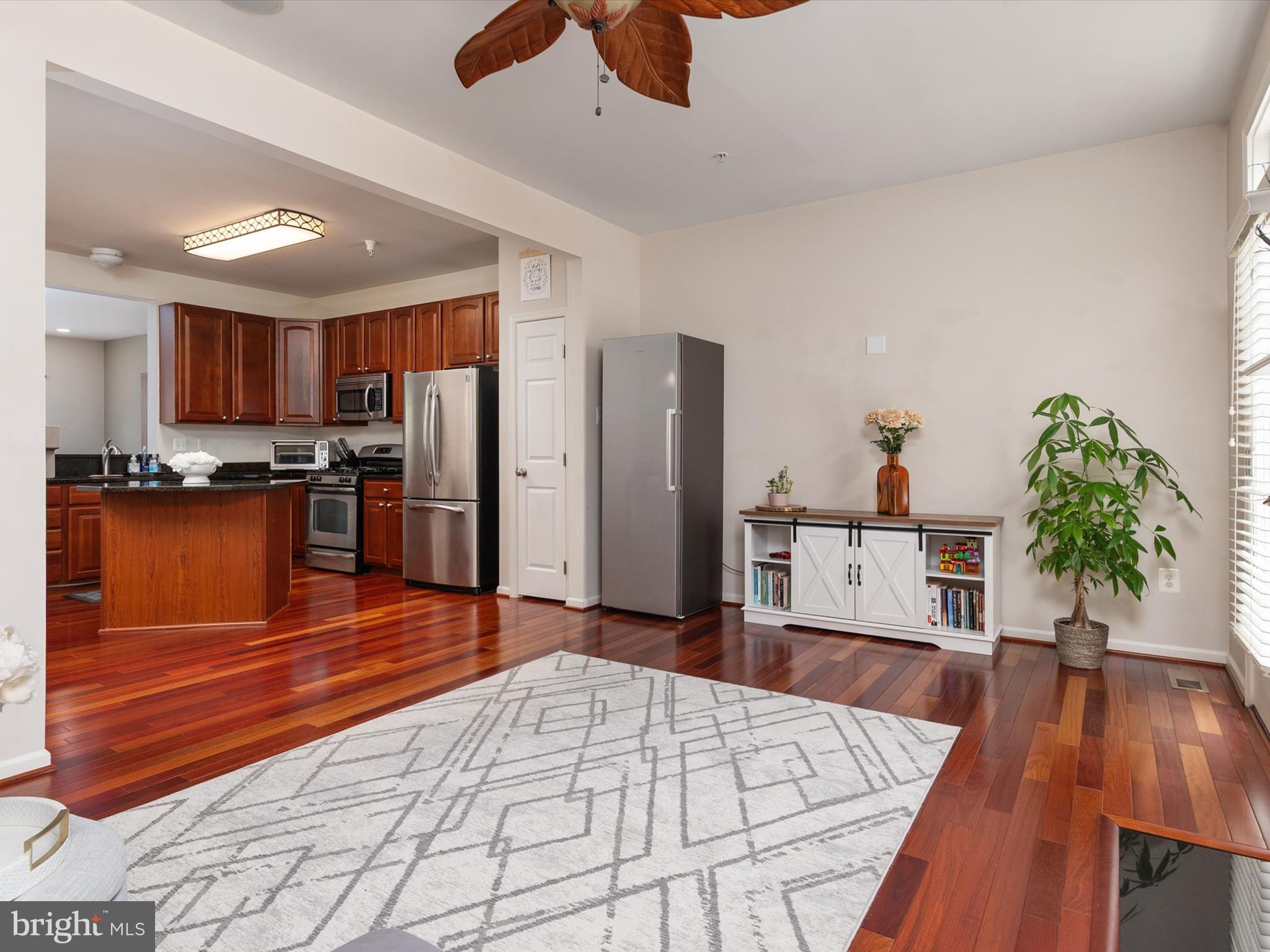 6888 Tasker Falls Elkridge, MD 21075 - Photo 23 of 47 a large kitchen with stainless steel appliances kitchen island granite countertop a table chairs in it and wooden floors