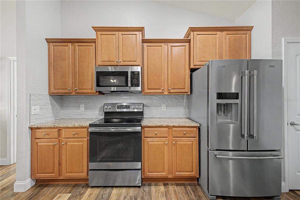 11213 Flock Avenue Weeki Wachee, FL 34613 - Photo 10 of 46 a kitchen with granite countertop a refrigerator stove and microwave