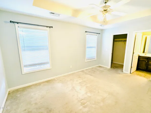 a view of an empty room with chandelier fan and a window
