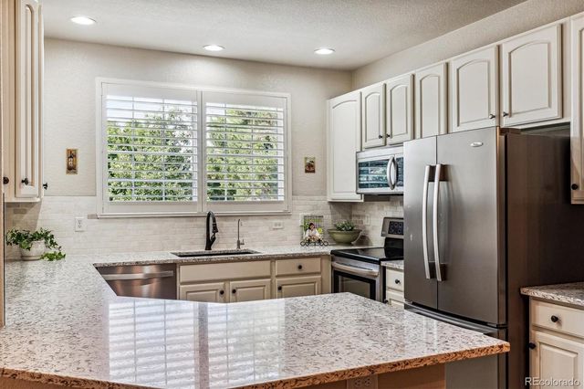 a kitchen with stainless steel appliances granite countertop a sink a stove and a refrigerator