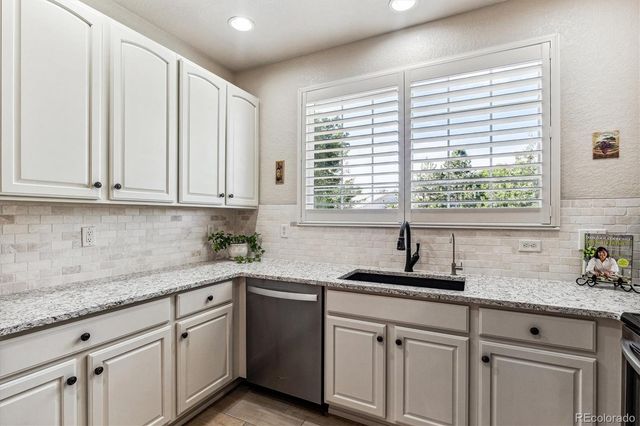 a kitchen with granite countertop a sink and white cabinets