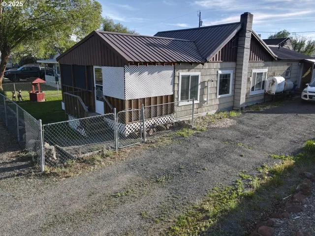 a backyard of a house with wooden fence and a tree