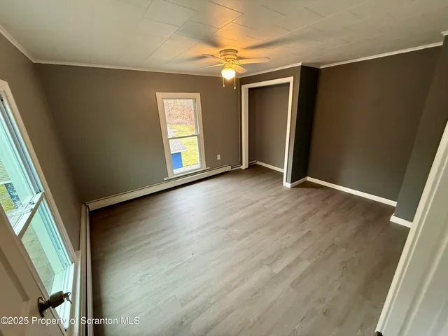 an empty room with wooden floor fan and windows