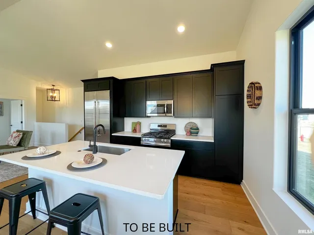 a kitchen with a stove a sink and a living room