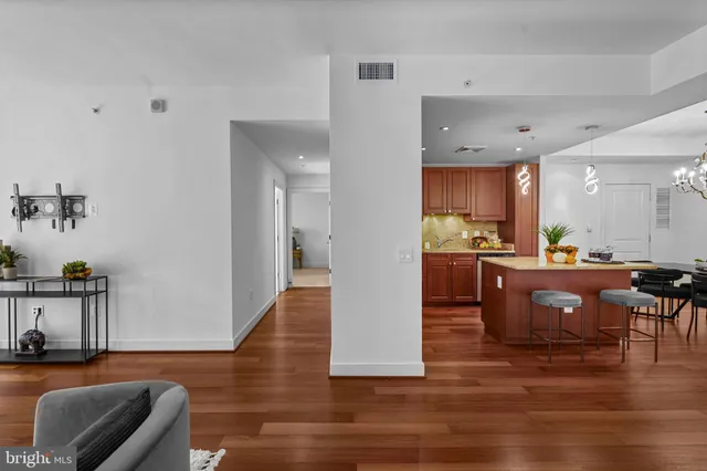 a kitchen with stainless steel appliances a sink dishwasher a stove top oven a refrigerator with wooden cabinets and floor