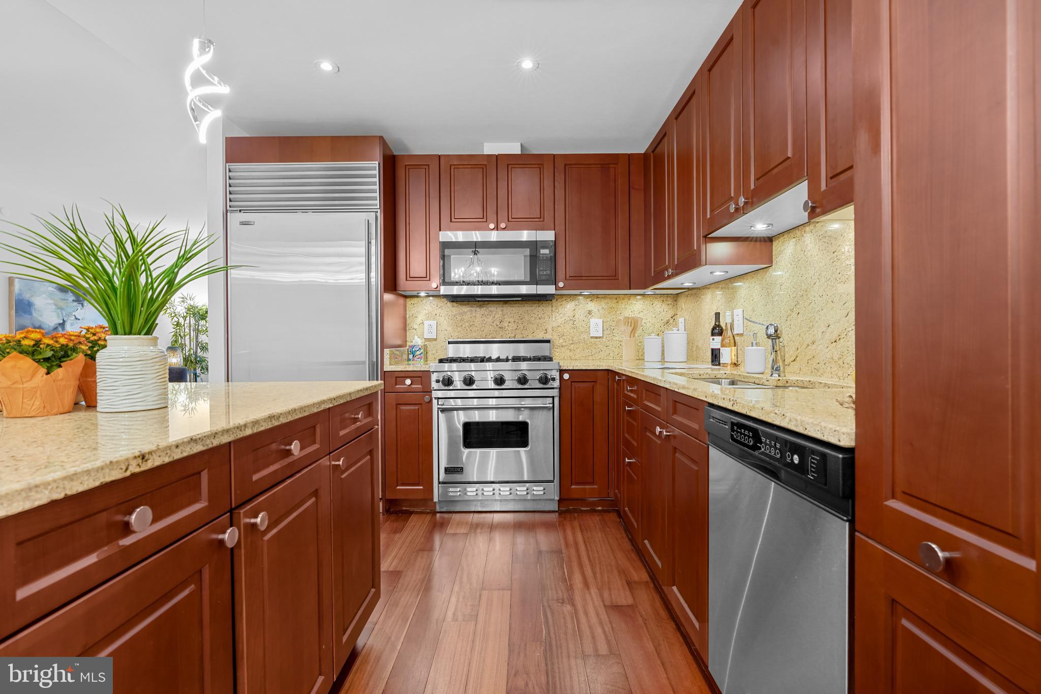 2425 L Street Northwest, Unit 431 Washington, DC 20037 - Photo 12 of 29 a kitchen with stainless steel appliances a sink dishwasher a stove top oven a refrigerator with wooden cabinets and floor