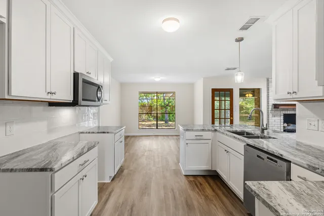 a kitchen with granite countertop a sink a counter space stainless steel appliances and cabinets