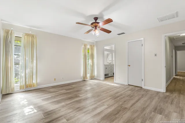 a view of empty room with wooden floor and fan