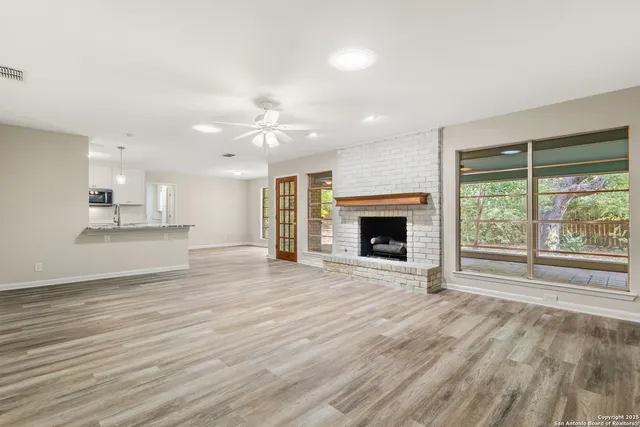 an empty room with wooden floor a fireplace and windows