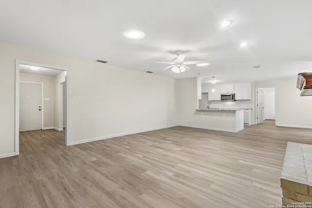 a view of kitchen and empty room with wooden floor