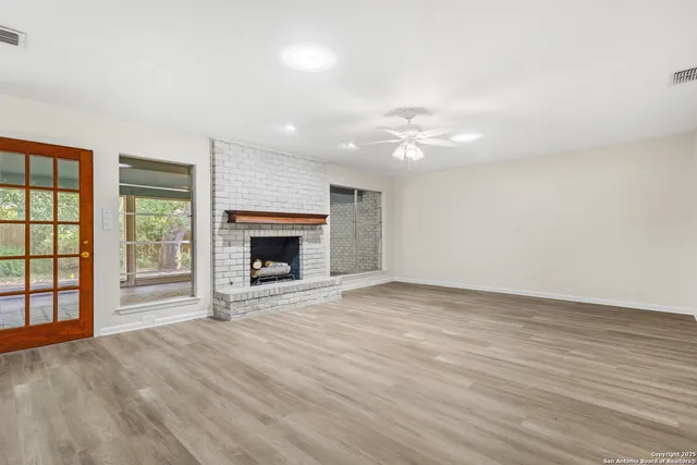 an empty room with windows and fireplace