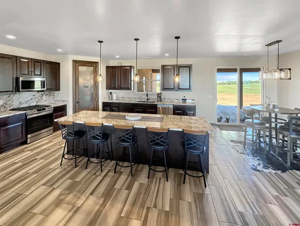 a large kitchen with kitchen island granite countertop lots of counter space a sink appliances and a dining table