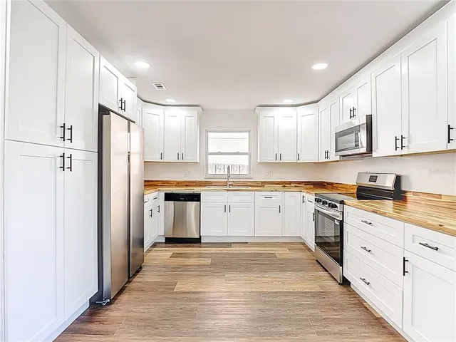 a kitchen with granite countertop white cabinets and stainless steel appliances