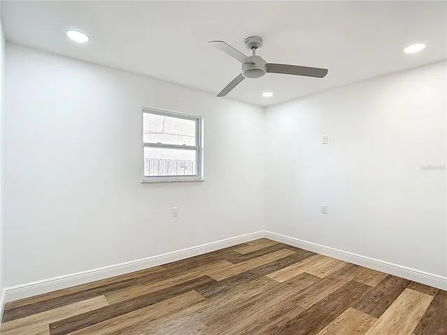 an empty room with a window and ceiling fan