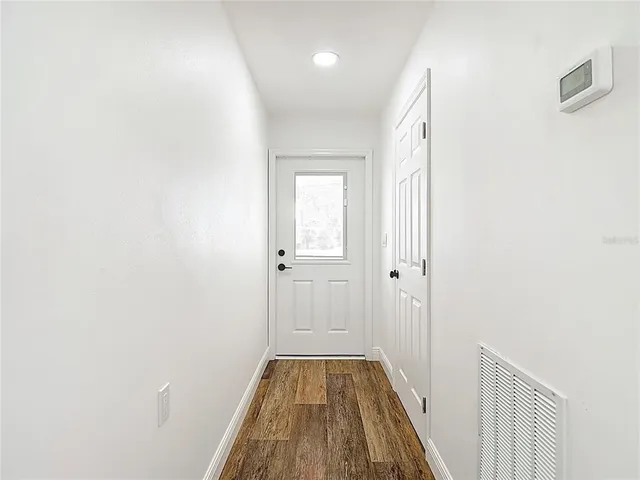 a view of a hallway with wooden floor and a bathroom