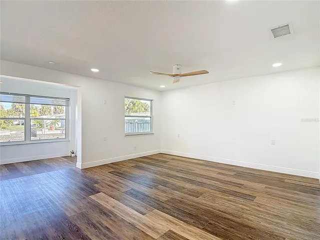 an empty room with wooden floor and windows