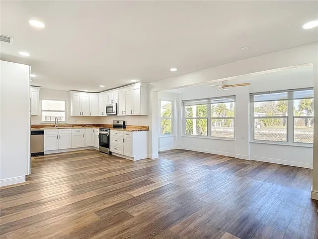 a large kitchen with wooden floors and white cabinets