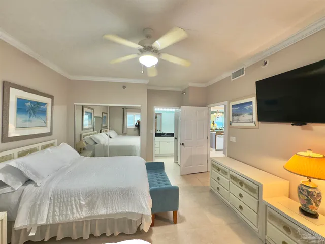 a bedroom with a bed a flat tv screen and a chandelier