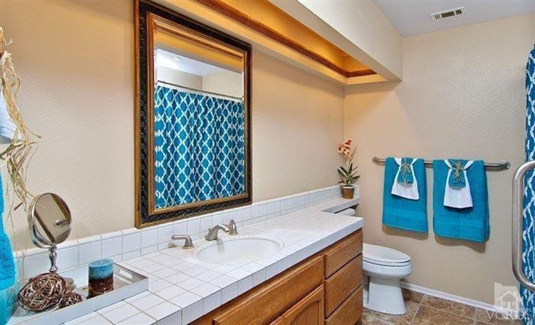 2921 Fanshell Walk Oxnard, CA 93035 - Photo 10 of 20 a bathroom with a sink a toilet and shower curtain