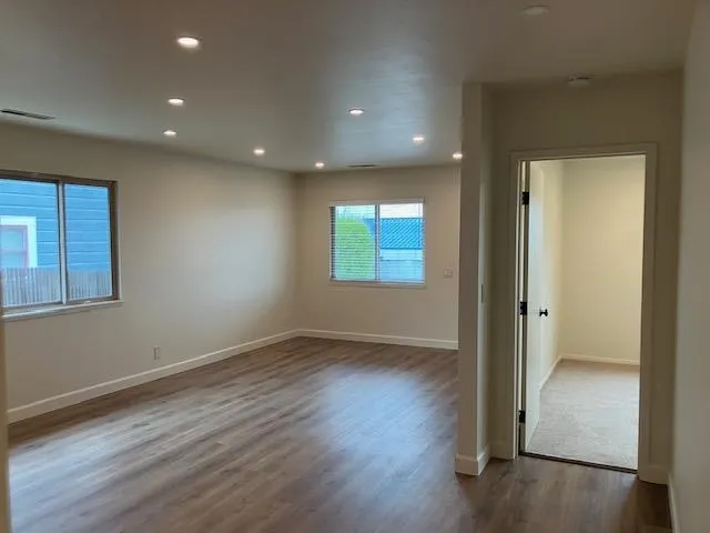a view of an empty room with wooden floor and a window