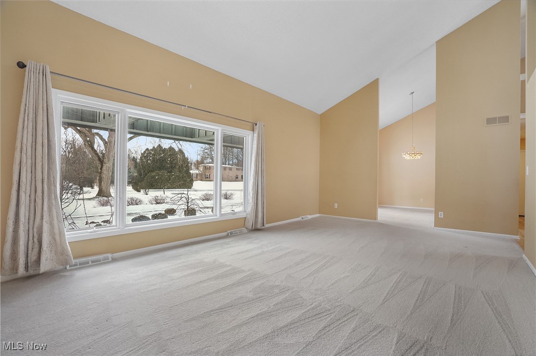 1094 San Raphael Drive Akron, OH 44333 - Photo 11 of 50 Empty room with high vaulted ceiling, light carpet, and a chandelier