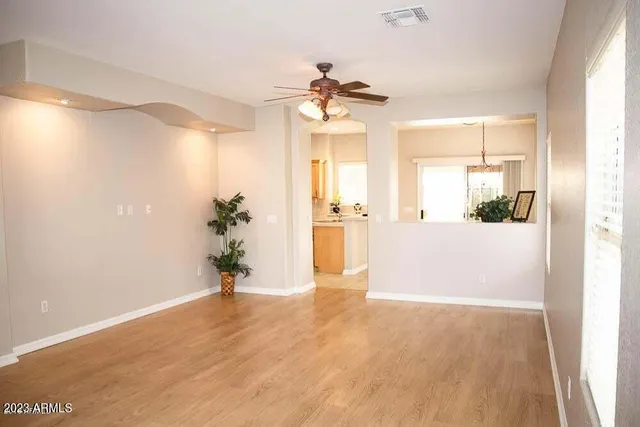 a view of a big room with wooden floor and a chandelier fan