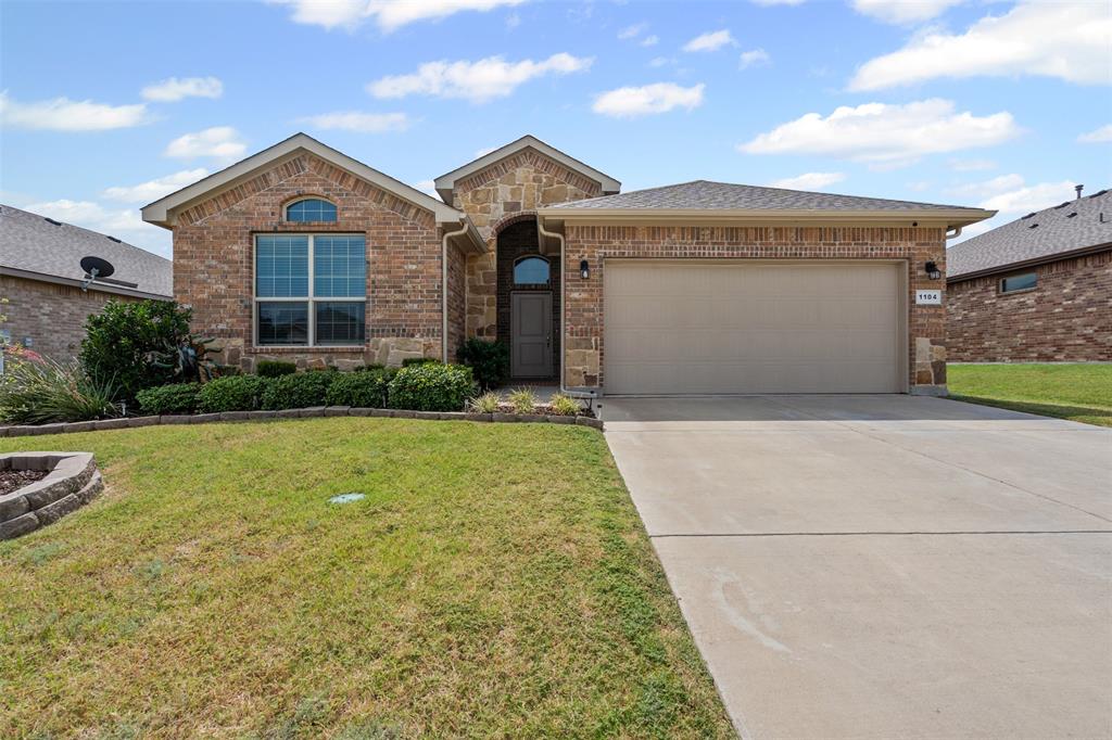 View of front of house with brick siding, a front lawn, driveway, and an attached garage