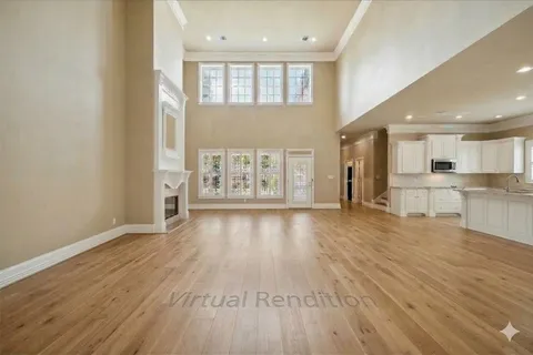 a view of an empty room and kitchen with wooden floor