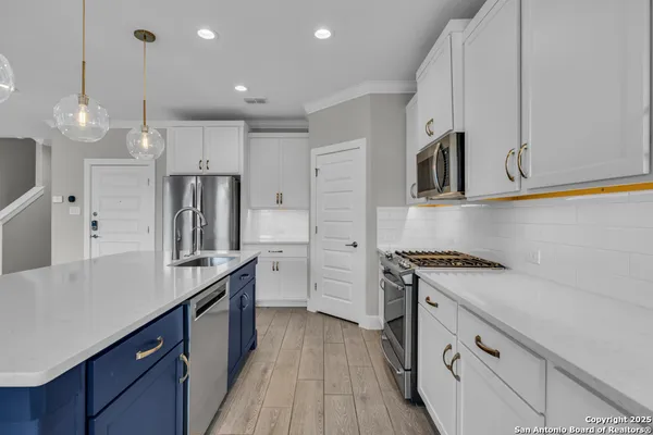 a kitchen with stainless steel appliances granite countertop a sink a stove a refrigerator and island with wooden floor