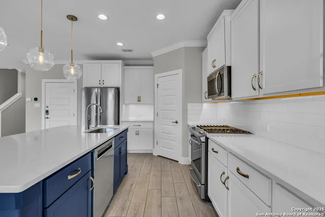 a kitchen with stainless steel appliances granite countertop a sink a stove a refrigerator and island with wooden floor