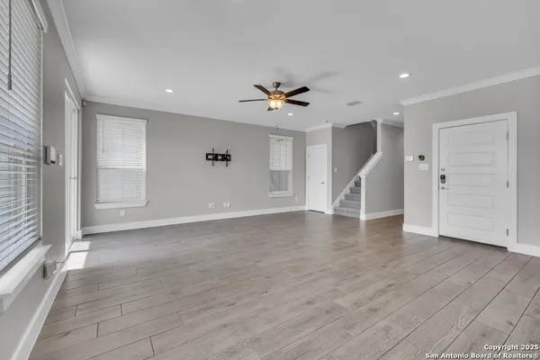 a view of an empty room with wooden floor and a ceiling fan